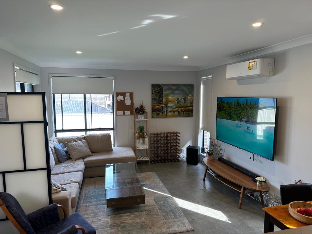 een woonkamer met een bank en een flatscreen-tv bij Cool Air Austral with AC in Austral