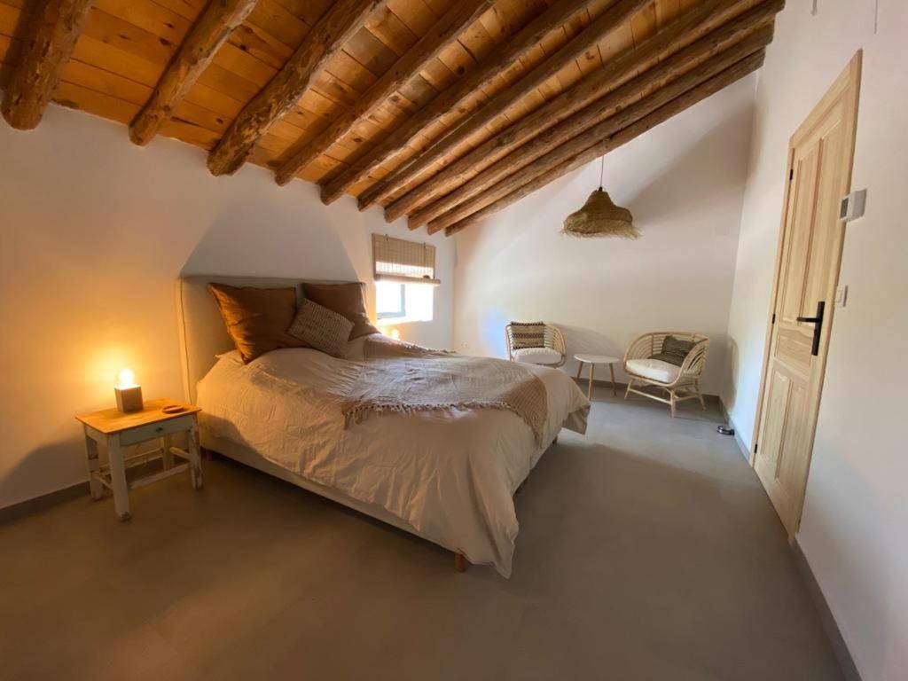 a bedroom with a large bed and a chair at Finca Las Botas in Almansa
