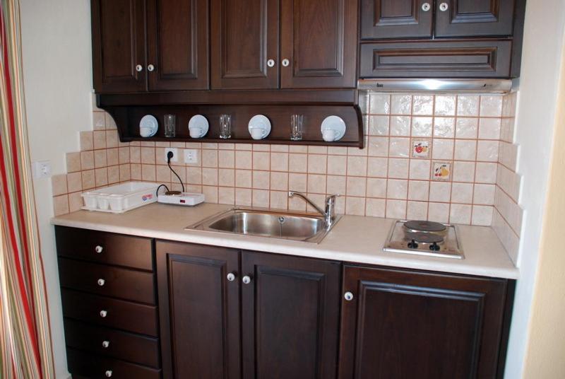 a kitchen with wooden cabinets and a sink at Pansion Nikos in Patitiri