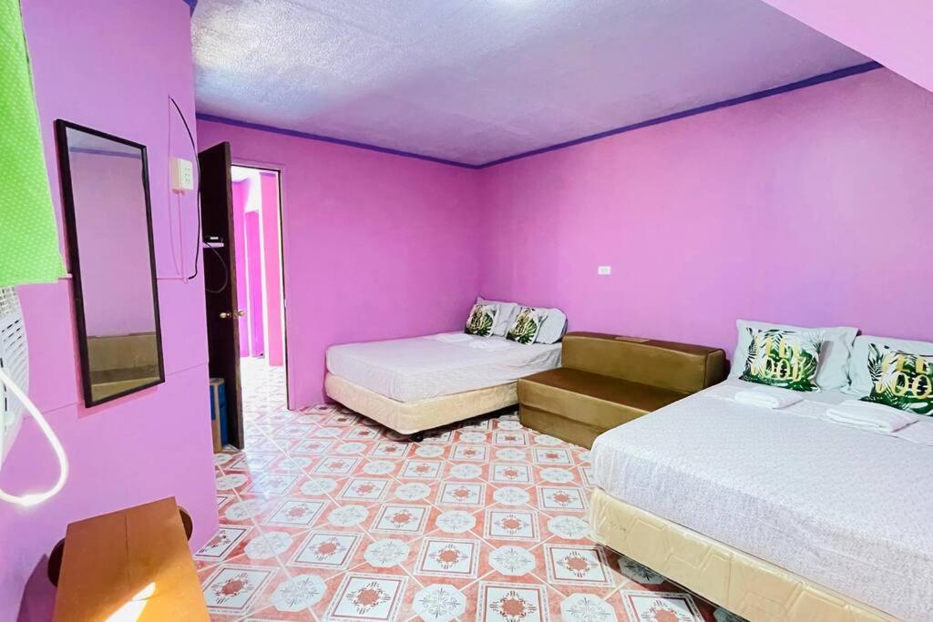 Pokój z 2 łóżkami i fioletową ścianą w obiekcie Einel Homestay 2 w mieście Siquijor