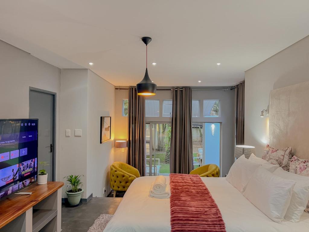una camera da letto con un letto grande e una TV di Amoris Guesthouse - Sandton a Johannesburg