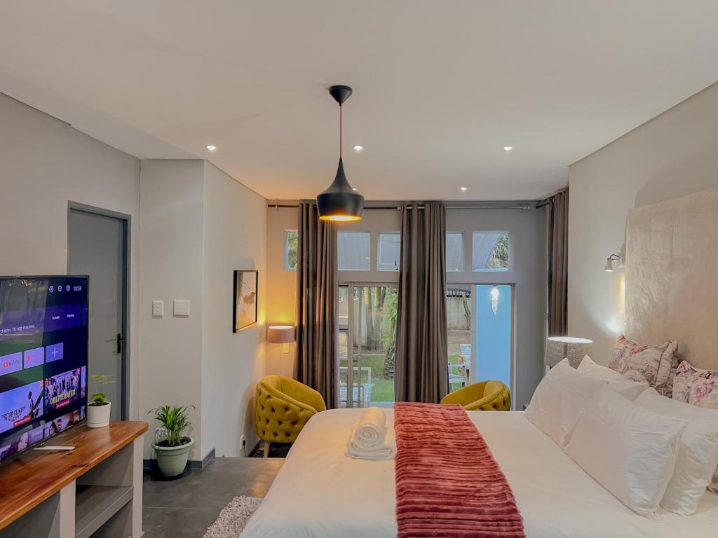 1 dormitorio con 1 cama grande y TV en Amoris Guesthouse - Sandton, en Johannesburgo