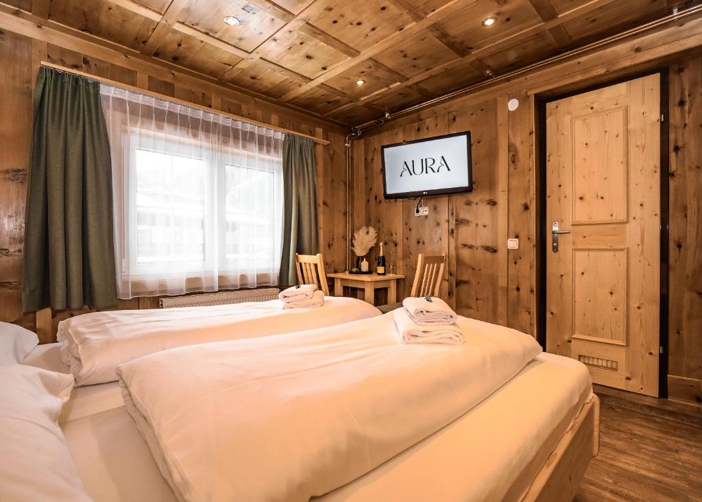 two beds in a room with a tv on the wall at AURA Bed & Breakfast in Sankt Jakob in Defereggen