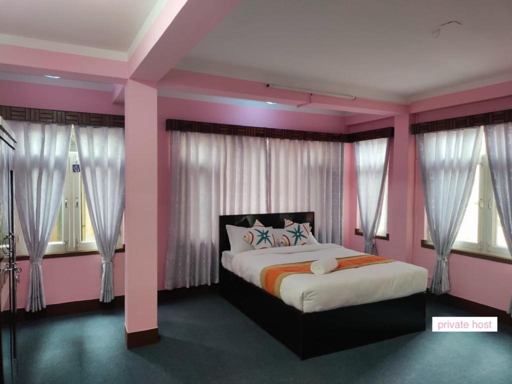 a bedroom with a bed with pink walls and windows at Andrew Home in Kathmandu