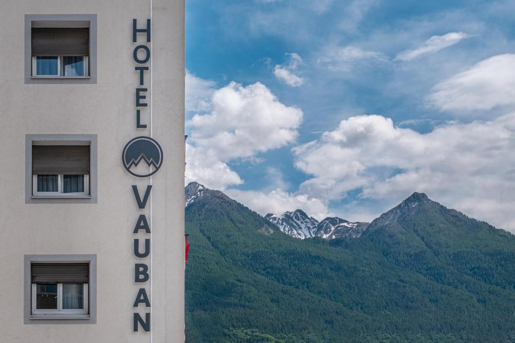 a hotel sign with mountains in the background at Hôtel Vauban Briançon Serre Chevalier in Briançon