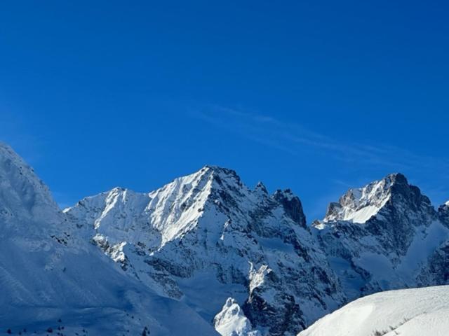 a snow covered mountain with a blue sky in the background at Hôtel Vauban Briançon Serre Chevalier in Briançon