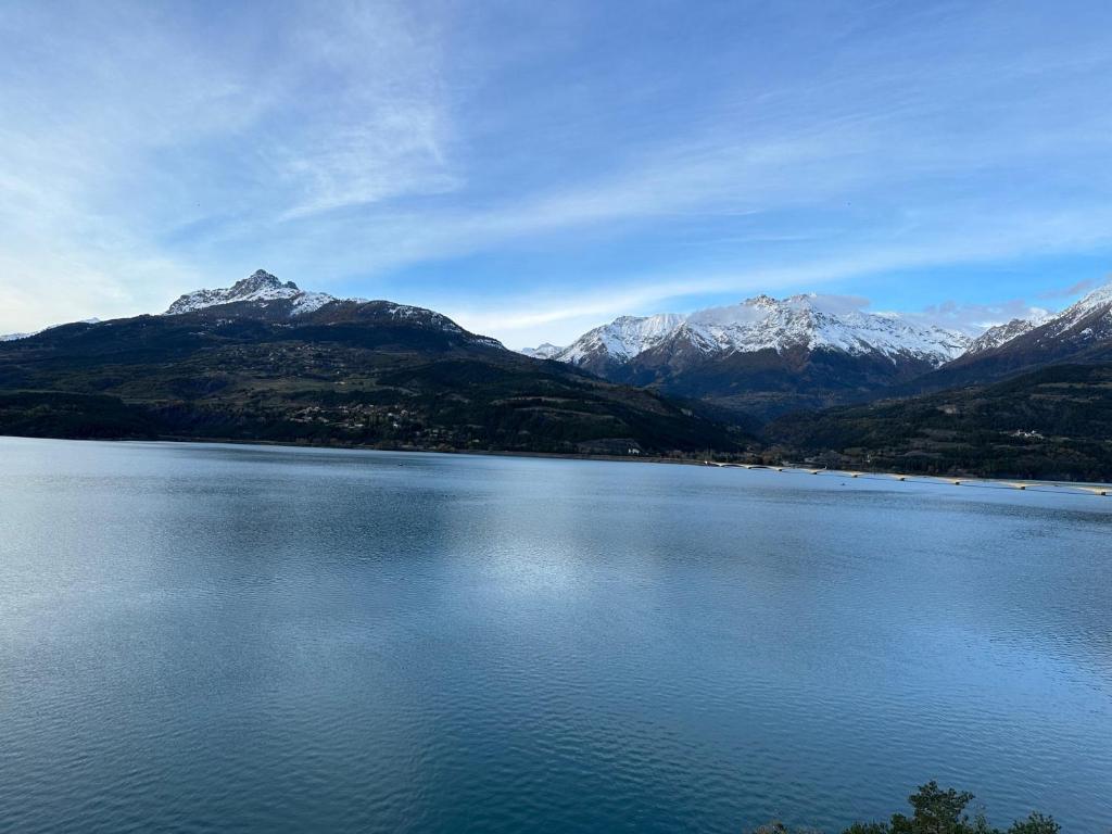 a large lake with snow capped mountains in the background at Hôtel Vauban Briançon Serre Chevalier in Briançon