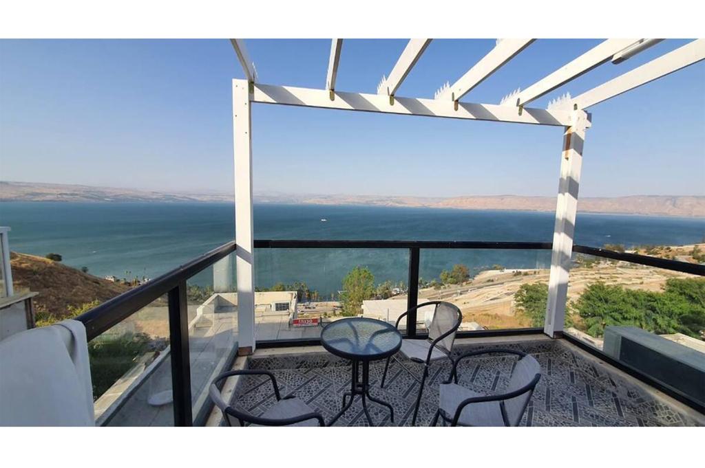 a balcony with chairs and a table and a view of the ocean at Sea of Galilee Panorama Apartment by Sea N' Rent in Tiberias