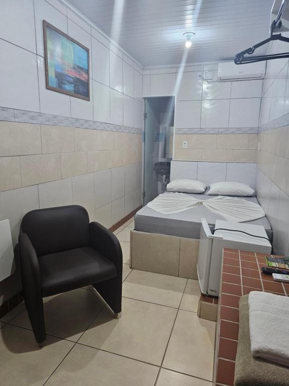 a small room with a bed and a chair at Arahra Hotel in Aparecida de Goiânia