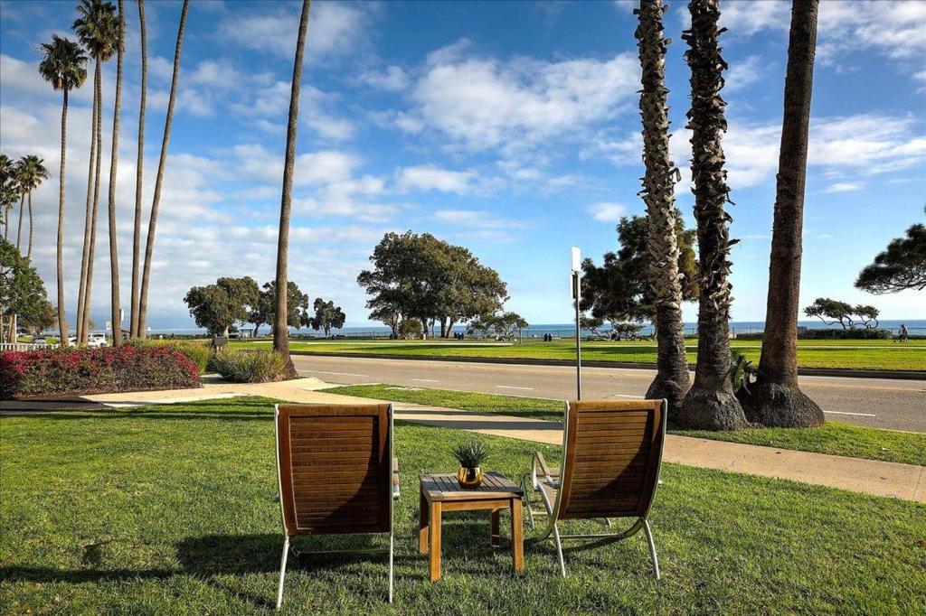 two chairs and a table in a park with palm trees at Shoreline Cottage in Santa Barbara
