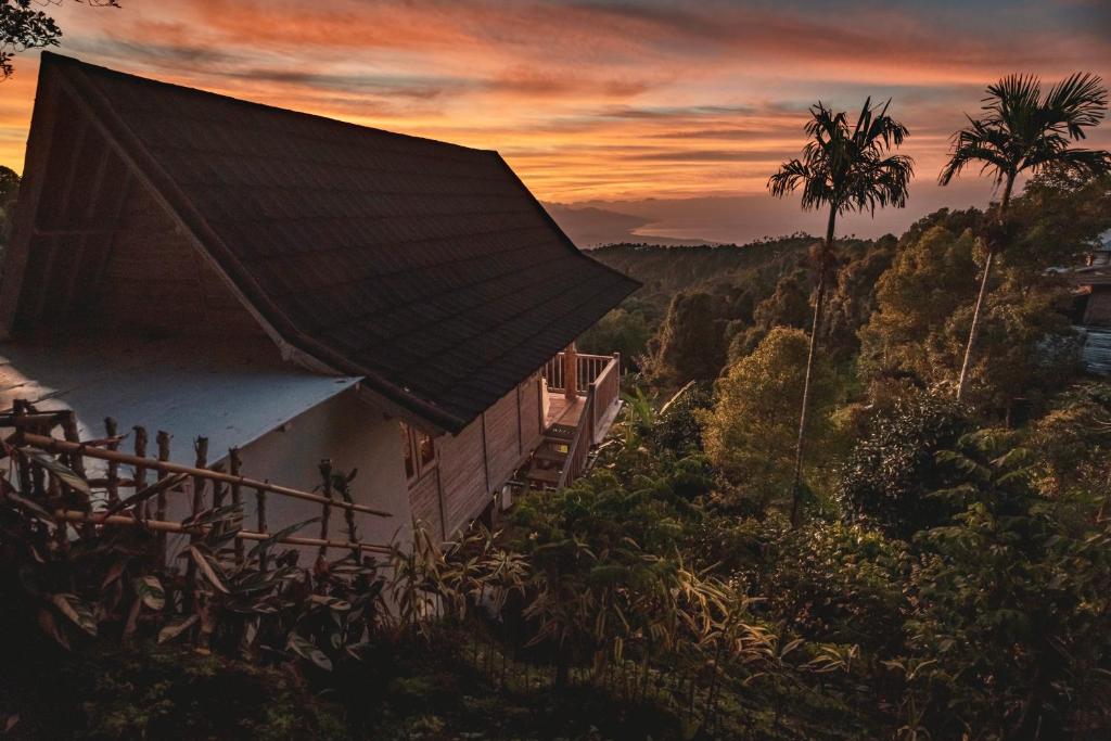 a house on a hill with a sunset in the background at Garden Terrace Bali in Gobleg
