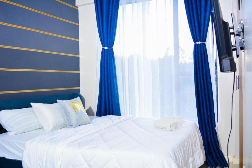 a bedroom with a bed with blue walls and a window at Residence Next Door Coral in Kiambu
