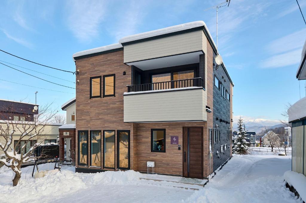 a wooden house with a balcony in the snow at KOYO・YUKI in Furano