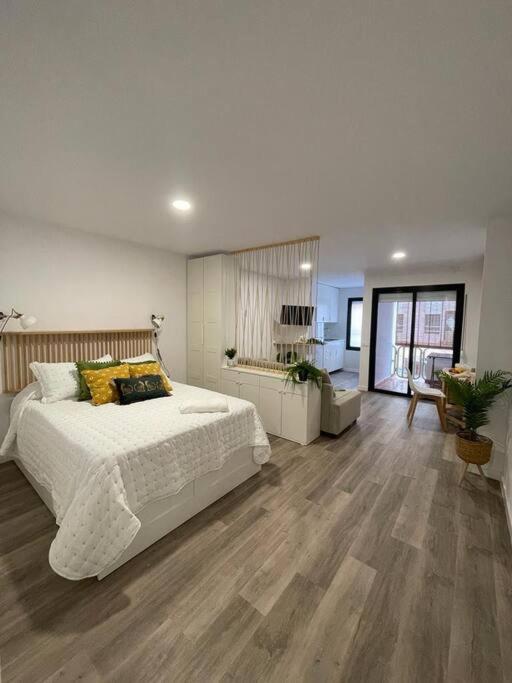 a bedroom with a large white bed and wooden floors at Apartamento Verde en Sotogrande in Sotogrande