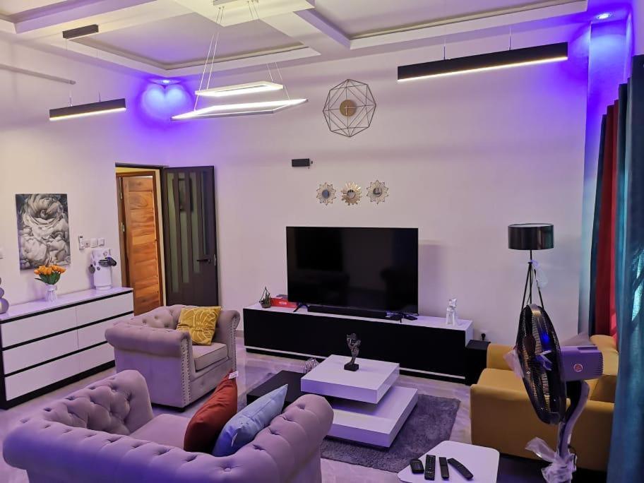 uma sala de estar com sofás e uma televisão de ecrã plano em YAYA em Cotonou