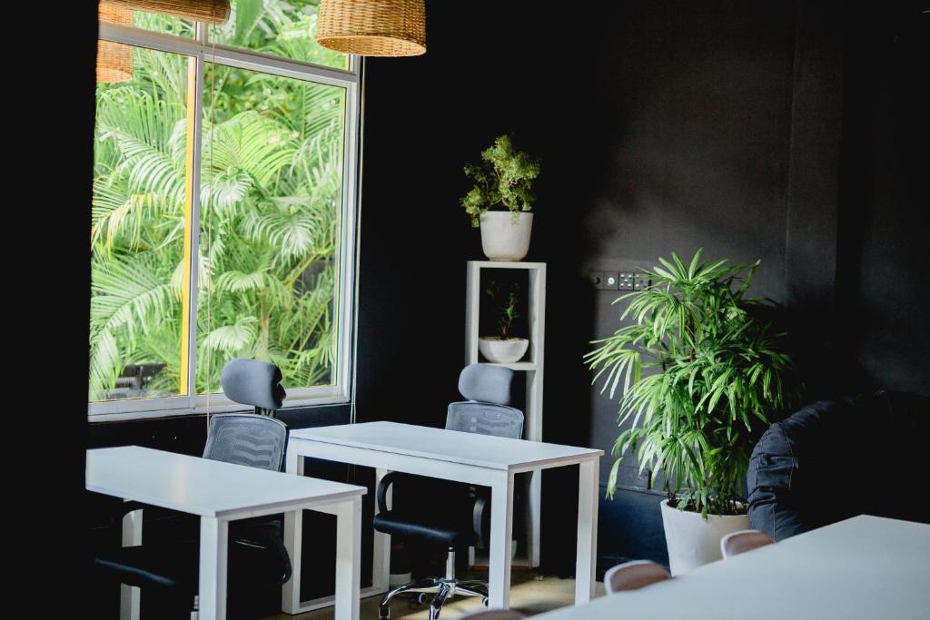 2 Tische und Stühle in einem Zimmer mit Pflanzen in der Unterkunft Sugar Hostel Weligama - Coliving & Coworking in Weligama