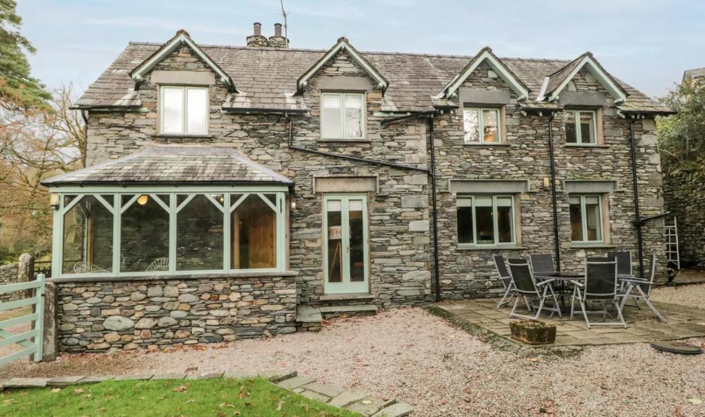 an external view of a stone house with a conservatory at Scandale Cottage in Ambleside