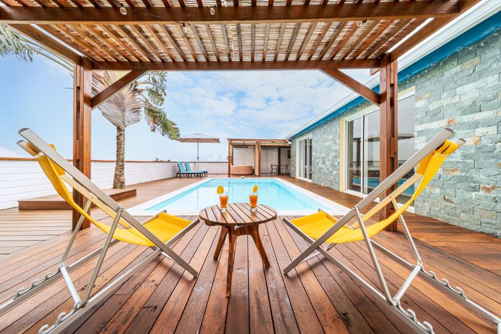 a deck with two chairs and a swimming pool at Bungalow L'escale de Takamaka in Saint-Benoît