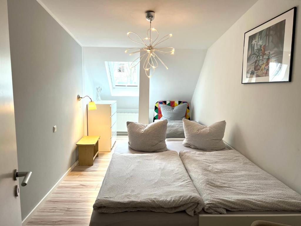 1 dormitorio con 2 camas y lámpara de araña en Hinterhaus Apartments, en Leipzig