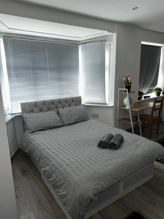 ein Schlafzimmer mit einem großen Bett mit zwei Hausschuhen darauf in der Unterkunft Modern studio flat in Romford in Havering atte Bower