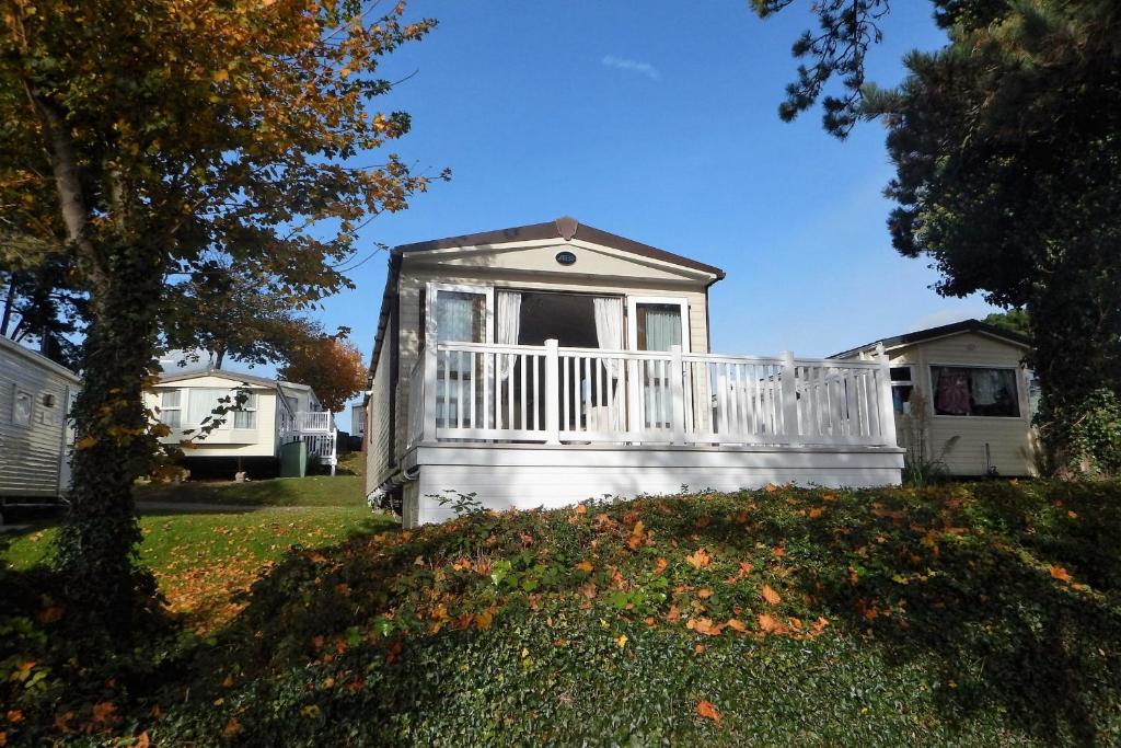 Cette petite maison blanche possède une terrasse couverte dans une cour. dans l'établissement Family Seaside Retreat Private Stay at 5-Star Rockley Holiday Park Poole, à Poole