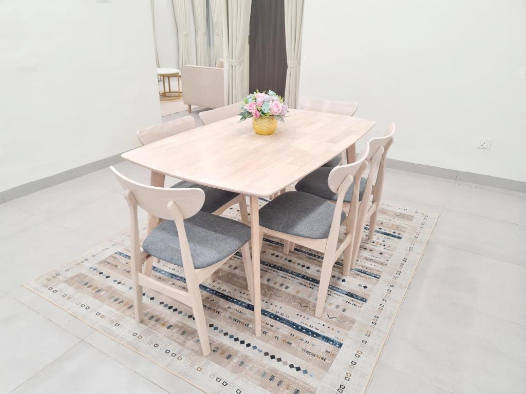 a wooden table and chairs with a vase of flowers at White Sweet Homestay, Kulim Hi-Tech Park Kedah utk MsIIim shj in Kulim