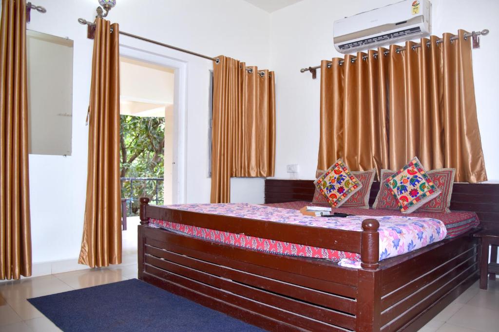 a bedroom with a large bed with orange curtains at Gir Pride Resort in Sasan Gir