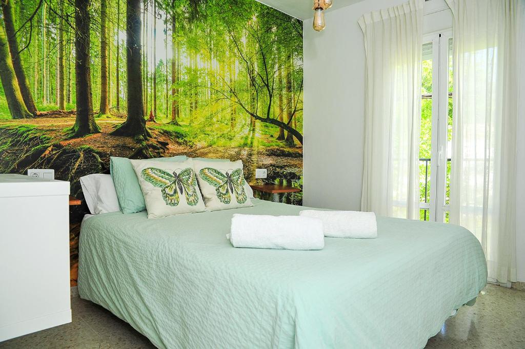 um quarto com uma cama com um mural de floresta na parede em Apartamento El Sendero em El Bosque