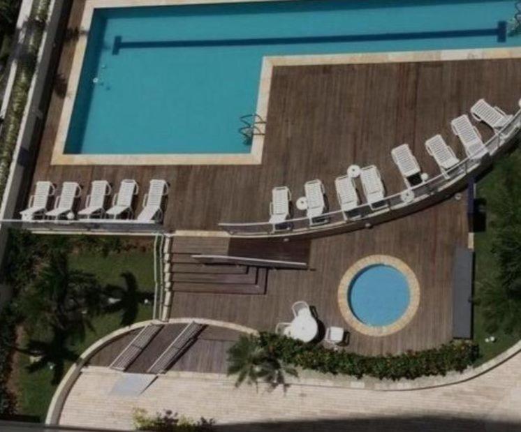 a large swimming pool with chairs and a swimming pool at Apartamento na Praia das Asturias - Pé na Areia in Guarujá