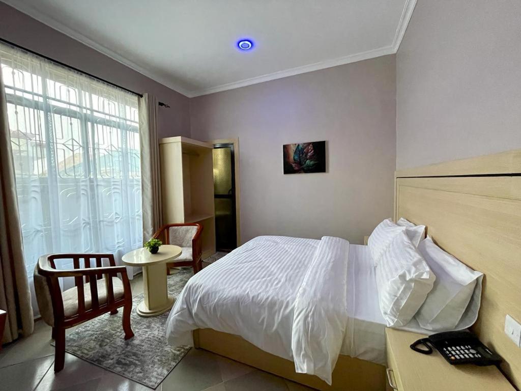 a bedroom with a bed and a chair and a table at Rosa Hotels in Dodoma