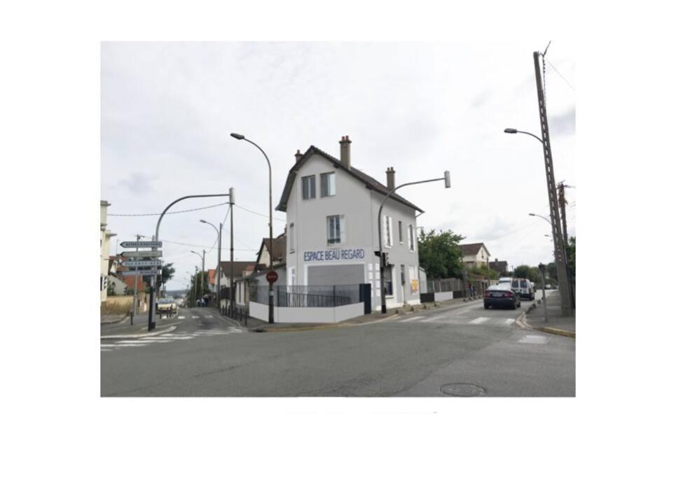 un bâtiment blanc au coin d'une rue dans l'établissement Maison de Ville Complète proche Paris JO 16p, à Poissy