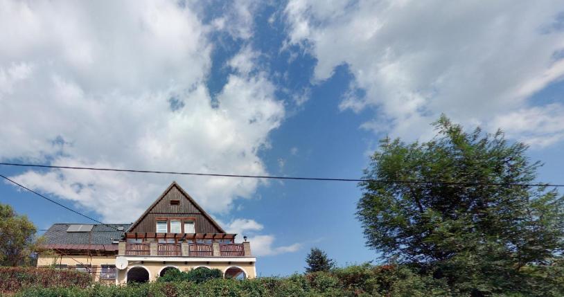 una casa sentada en la cima de una colina bajo un cielo nublado en Ubytování Na Stráni, en Jablonec nad Nisou