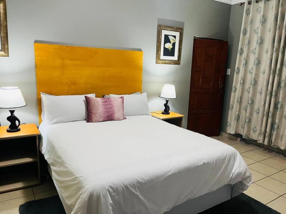 a bedroom with a large white bed with two lamps at Flat in Rustenburg in Rustenburg