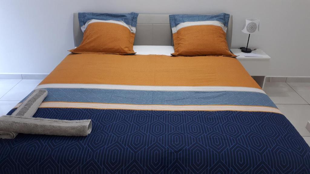 een bed met oranje en blauwe lakens en kussens bij Lala location Le Moule in Le Moule