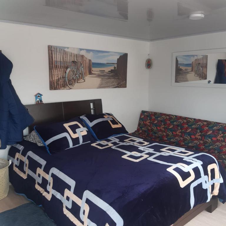 uma cama com uma colcha azul e branca e um sofá em Acogedora Habitación em Pasto