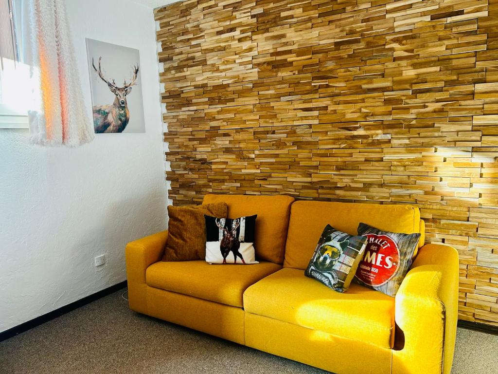 a yellow couch in a room with a brick wall at Eden Studio La foux d Allos centre station , 50 m du centre avec terrasse plein sud , chambre 4 couchages in La Foux