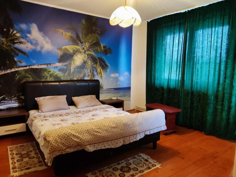 ein Schlafzimmer mit einem Bett und ein Wandbild eines Strandes in der Unterkunft Vila spatioasa 7 camere la lacul BUftea in Buftea