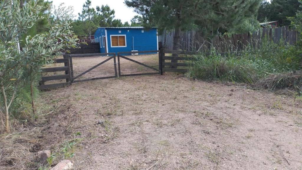 a blue dog house in a yard next to a fence at Cabañas azules in Punta Del Diablo