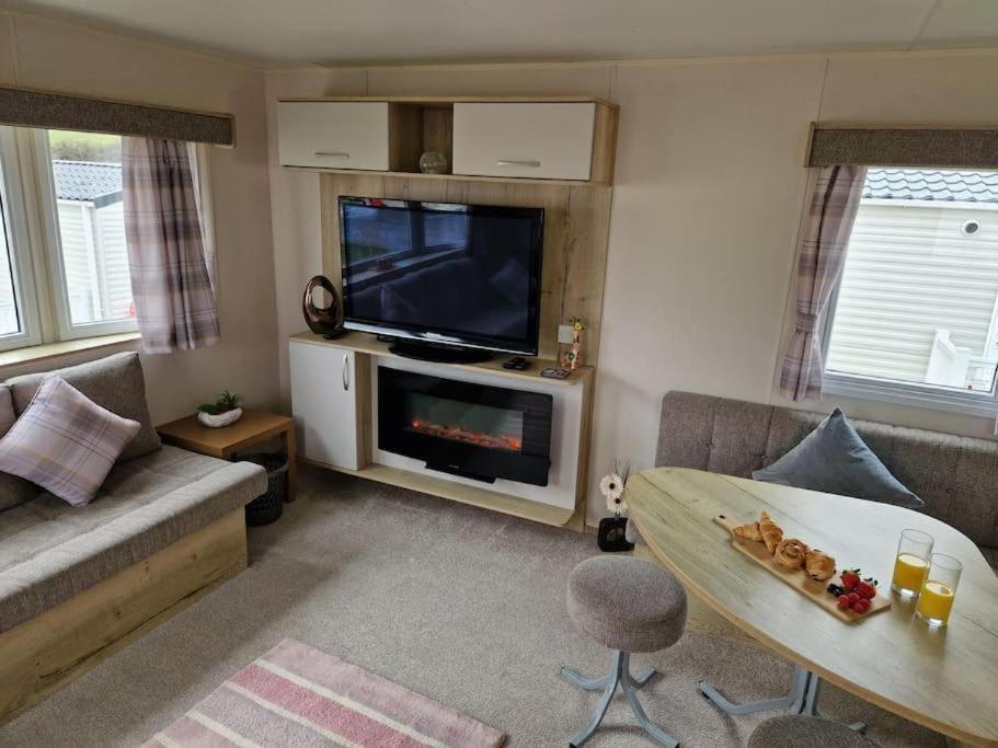 uma sala de estar com uma televisão, um sofá e uma mesa em Weymouth Bay Haven, Preston Road em Weymouth