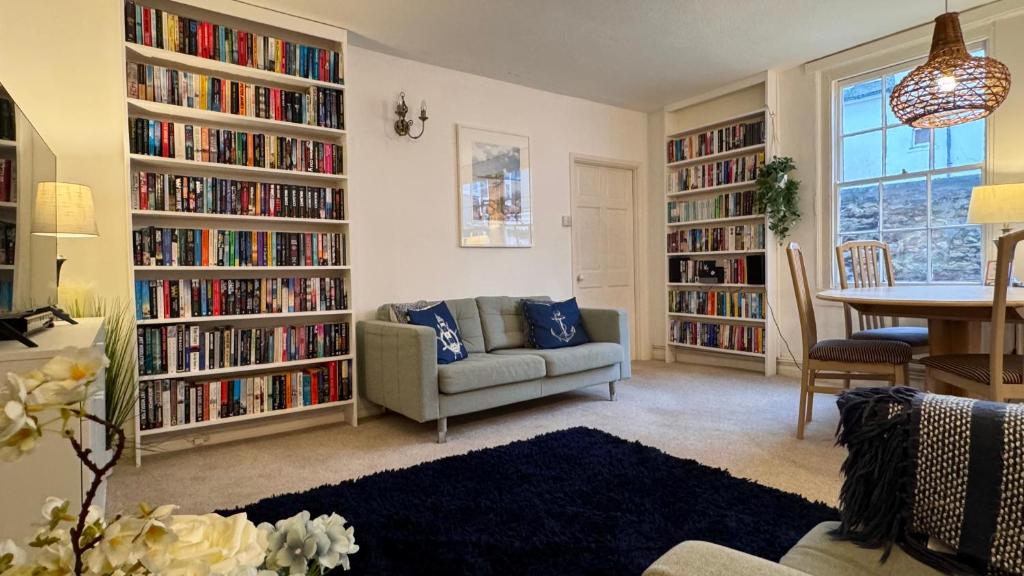 a living room with large book shelves filled with books at Dartmouth Town Centre 2 bedroom stylish apartment is perfect for families and couples with a happy & homely feel being only 30 meters from the sea but set back & quiet with everything on the doorstep a gorgeous place to explore the Devon beaches 5 star FB in Dartmouth