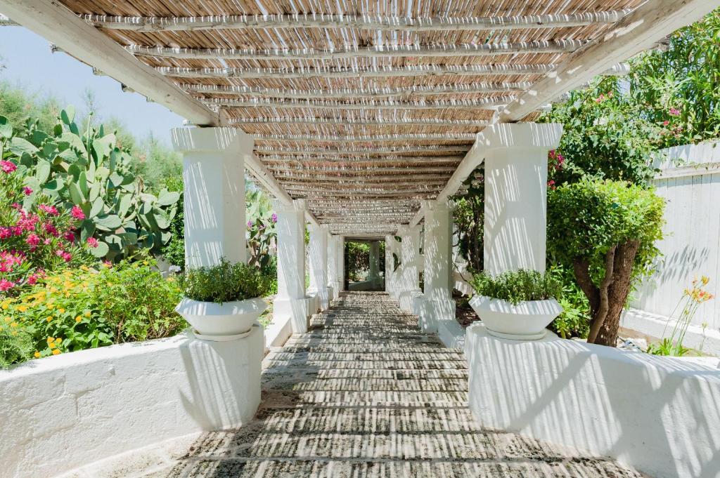 a white pergola with potted plants on it at La Peschiera in Monopoli