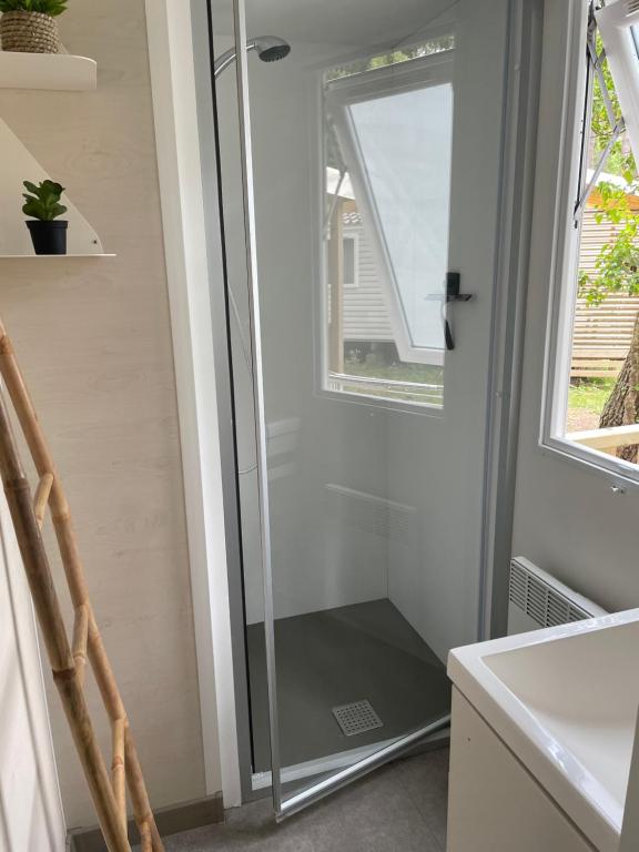 a glass shower door in a bathroom with a window at Au petit paradis in Camiers