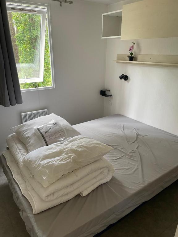 a white bed with white sheets and a window at Au petit paradis in Camiers