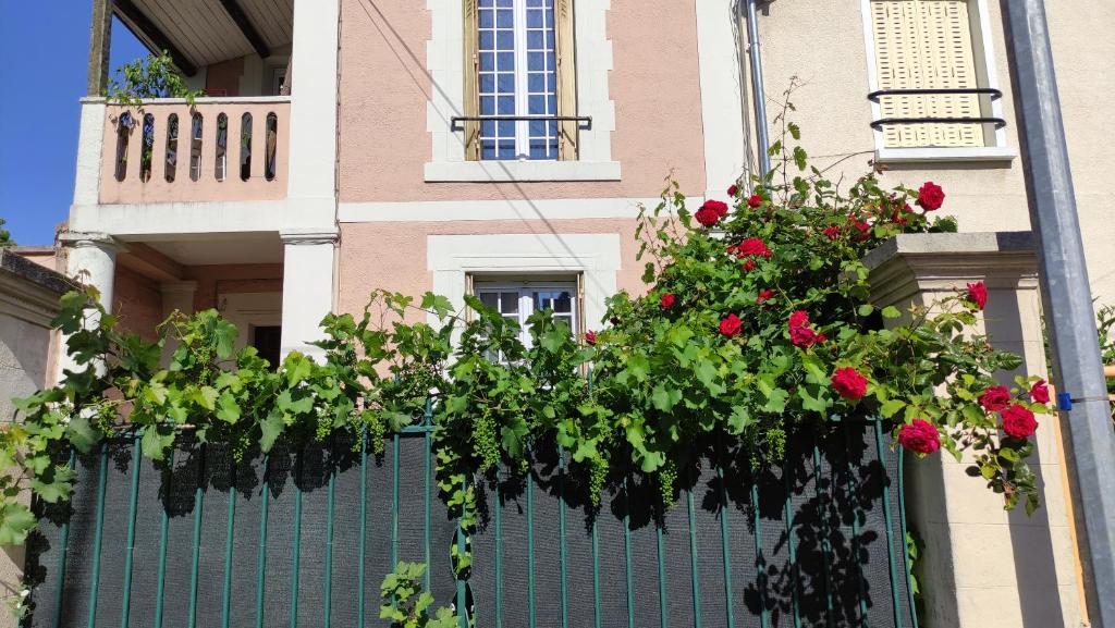 Ein Zaun mit roten Blumen vor einem Haus. in der Unterkunft Maison des Peupliers in Bondy