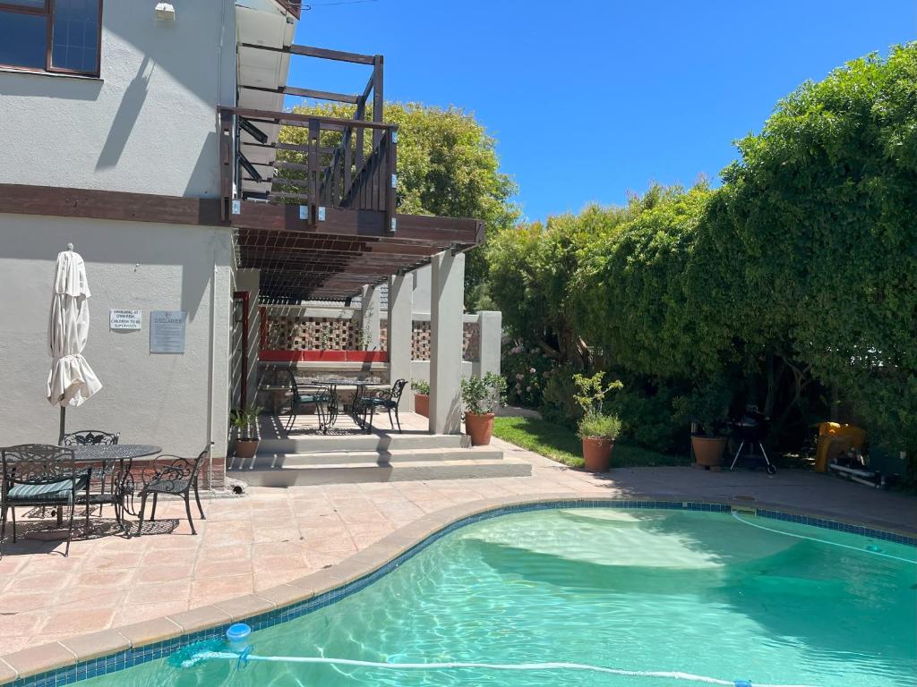 a swimming pool in front of a house with a patio at Pinoak Self Catering Cottages - Constantia in Cape Town