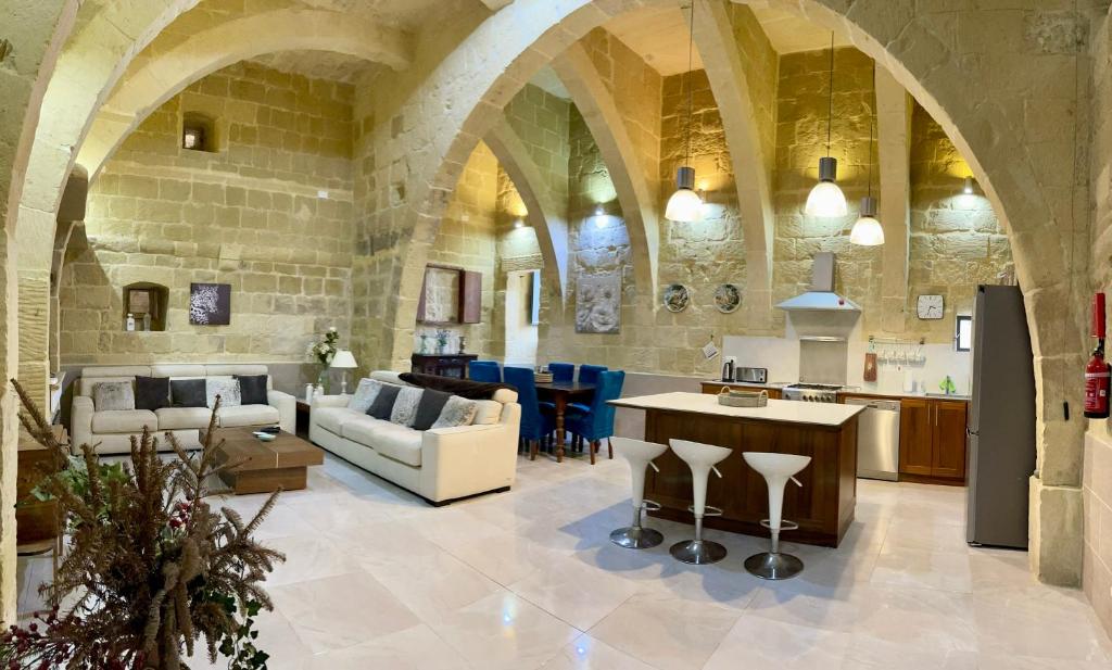 un grand salon avec un mur en pierre et une table dans l'établissement Daner Ta’ Pantu House, à Kerċem