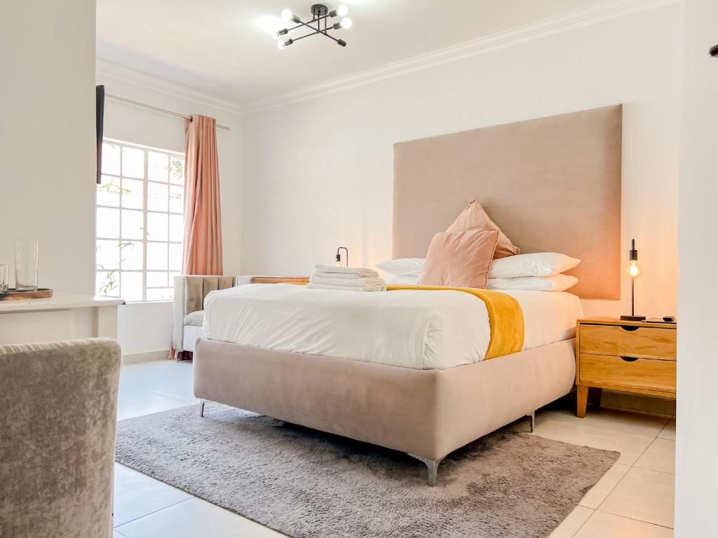 1 dormitorio con 1 cama grande con sábanas y almohadas blancas en Amoris Guesthouse - In Brooklyn en Pretoria