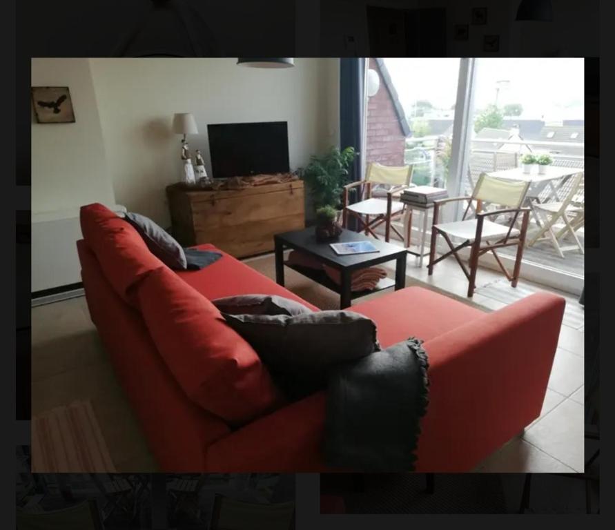 ein Wohnzimmer mit einem roten Sofa und einem Tisch in der Unterkunft Brise De Mer in Nieuwpoort