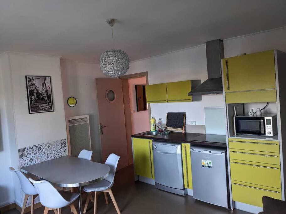 uma cozinha com armários amarelos e uma mesa com cadeiras em Appartement 4 voyageurs - Proche plage em Bray-Dunes