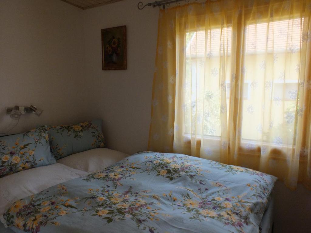 a bedroom with a bed with a floral comforter and a window at Müllers Ferienhäuser Gunaras & Harmonie in Gunaras in Dombóvár